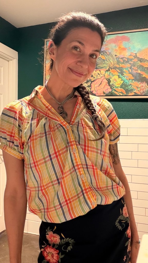 Lucy smiling indoors in front of an art piece